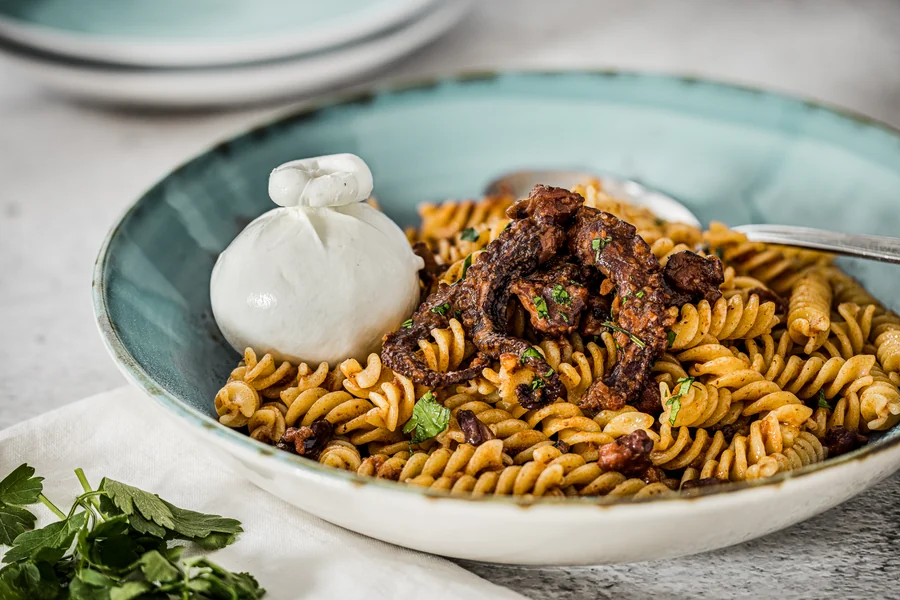 Dettaglio del ragù di polpo sui fusilli, con burrata e prezzemolo