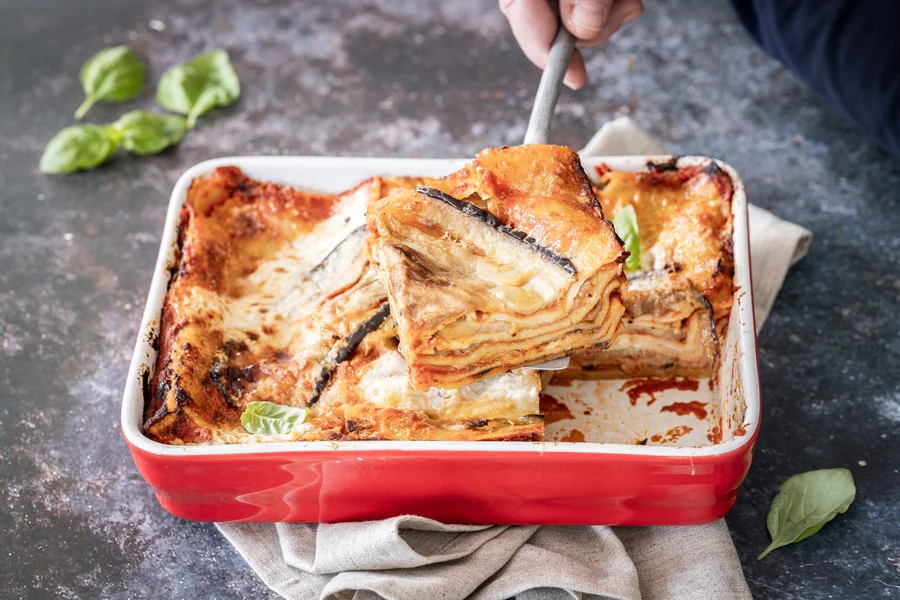 Porzione di lasagne alla parmigiana sollevata dalla teglia con una paletta